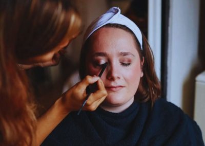 Susanne brengt make-up aan bij een klant met een haarband