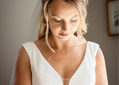 Bruid met blonde losse lokken kijkt naar beneden