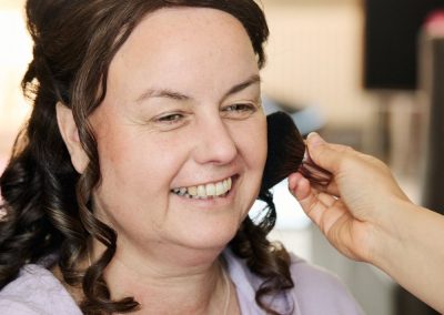 Bruid met donkere krullen tijdens het aanbrengen van make-up