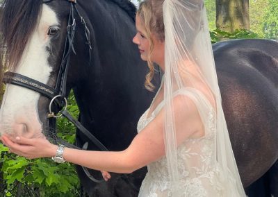 Bruid met sluier naast een zwart paard