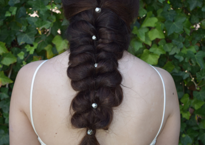 Achteraanzicht van een lange vlecht met kleine haaraccessoires