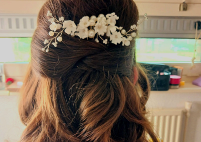 Half opgestoken bruin haar met een bloemvormig haaraccessoire